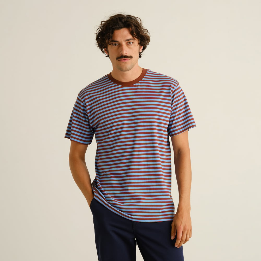 Front view of a model wearing the Stockholm T-shirt with cappuccino brown and cornflower blue horizontal stripes.