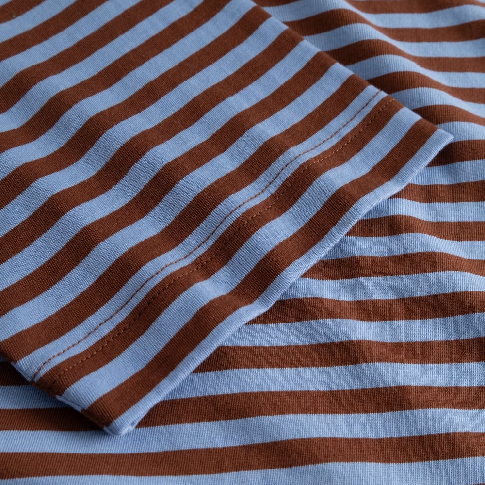 Close-up detail of the T-shirt Vadstena showing the soft striped fabric in cappuccino brown and cornflower blue.