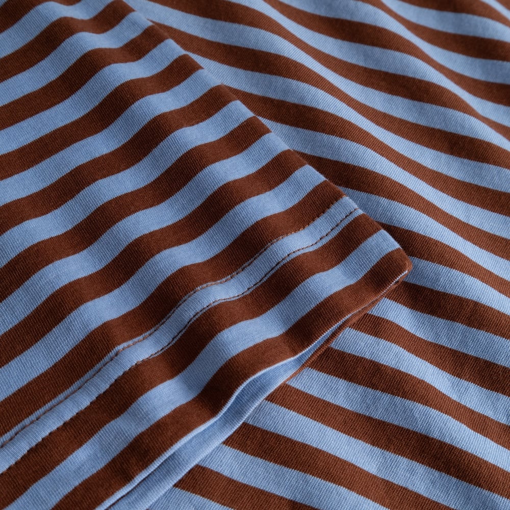 Close-up detail shot of the T-shirt Vadstena, showing the soft striped fabric in cappuccino brown and cornflower blue.