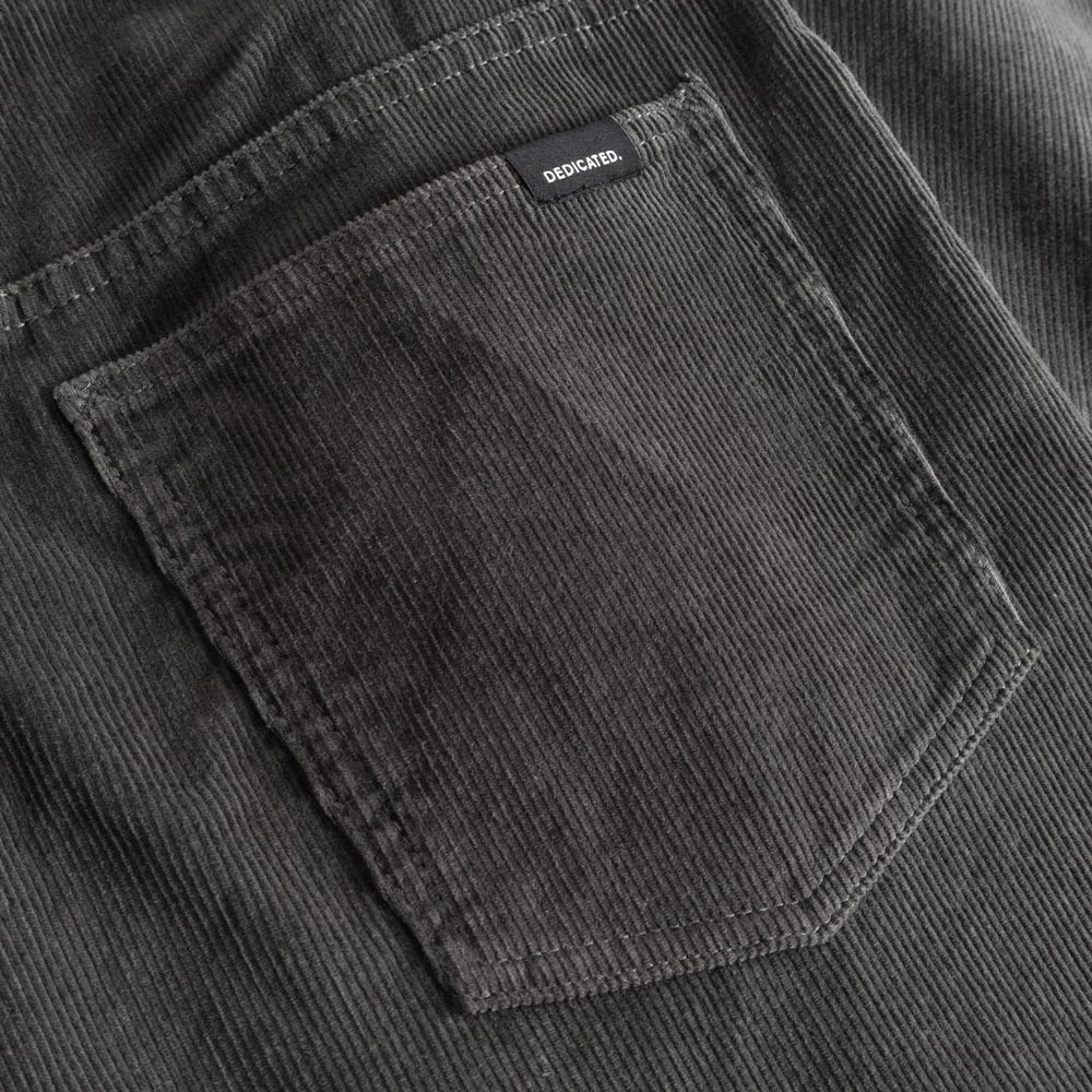 Detailaufnahme der Gesäßtasche der Cordhose Ryda in Rock Grey, die die klassische Textur und das Dedicated Label zeigt.