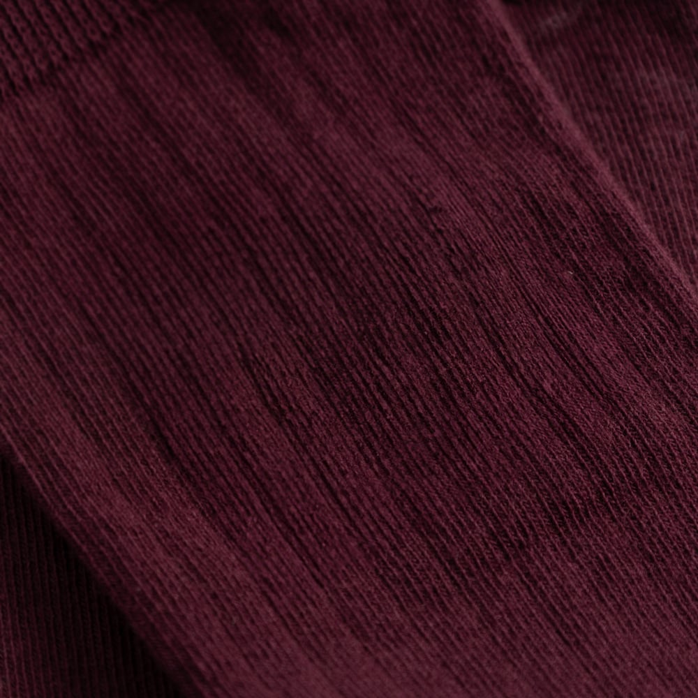 Close-up detail shot of the Rib Socks Knivsta, showing the fine ribbed texture in a deep Fig Red color.