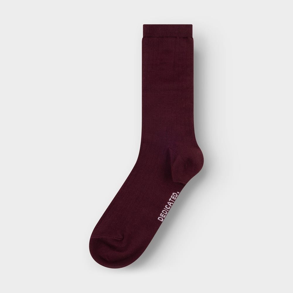A single Dedicated Rib Sock Knivsta in fig red, laid flat against a plain light grey background.