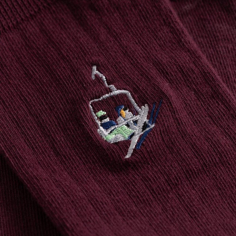 A detailed look at the fun ski lift embroidery on the fig red Knivsta ribbed socks.