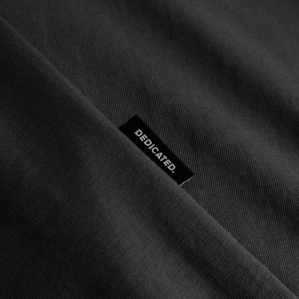 Close-up detail of the Dedicated brand label stitched onto the charcoal T-shirt Stockholm.