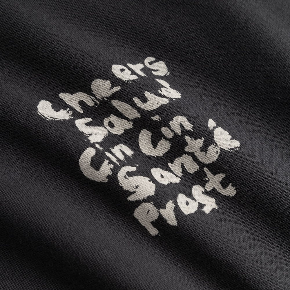 Close-up of the 'Cheers Salud' print in a textured, brush-stroke style on the charcoal Malmoe sweatshirt.