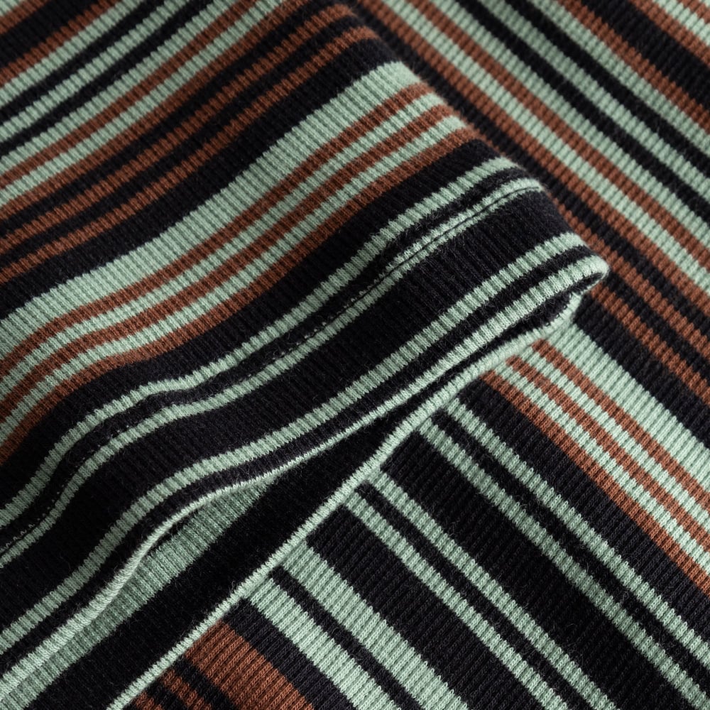 Close-up of the Rib Dress Lunsen showing the soft ribbed fabric with irregular stripes in green, black and brown.