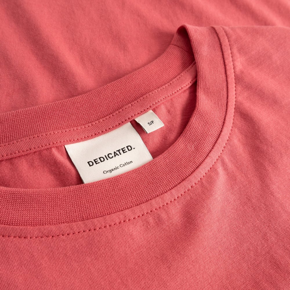 A detailed close-up of the T-shirt Vadstena in Holly Red, showing the fine ribbed collar and the Dedicated brand label.