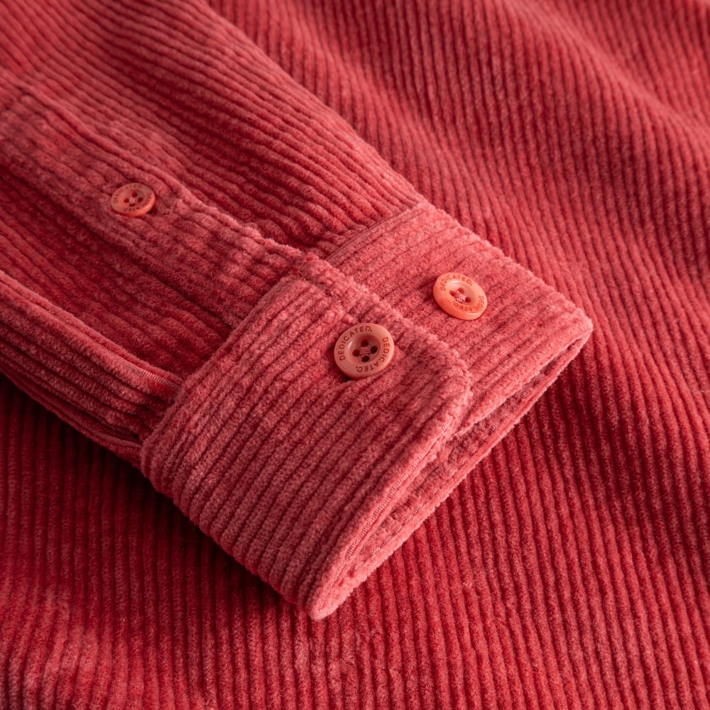 A close-up of the Shirt Kil Corduroy in Holly Red, showcasing the textured fabric and custom Dedicated buttons on the cuff.