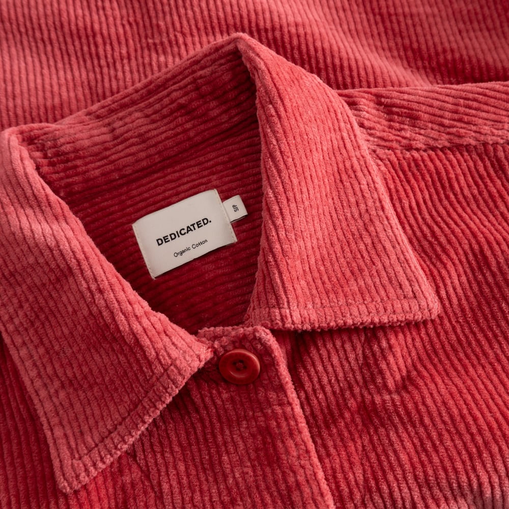 Close-up shot of the Dedicated brand label on the collar of the Stiby Corduroy Jacket in Holly Red.