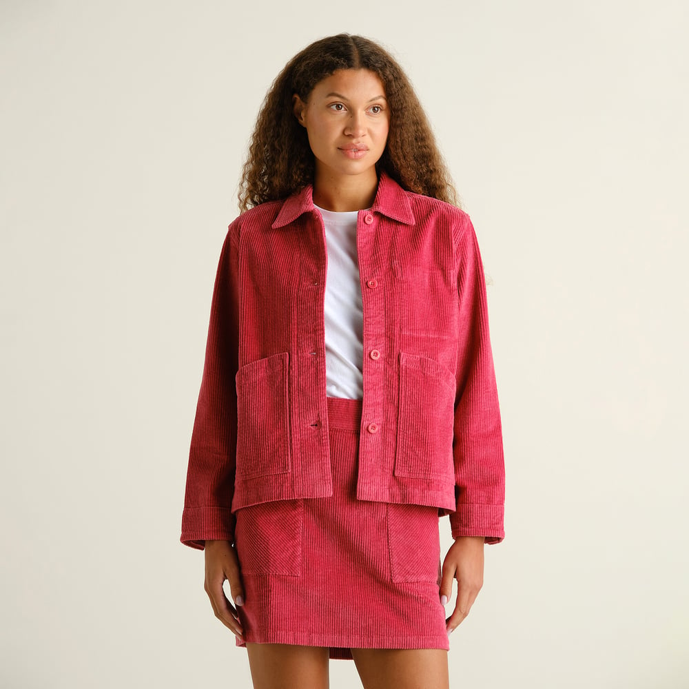 A model styles the Holly Red Stiby Corduroy Jacket with its matching skirt for a vibrant, coordinated look in our studio.