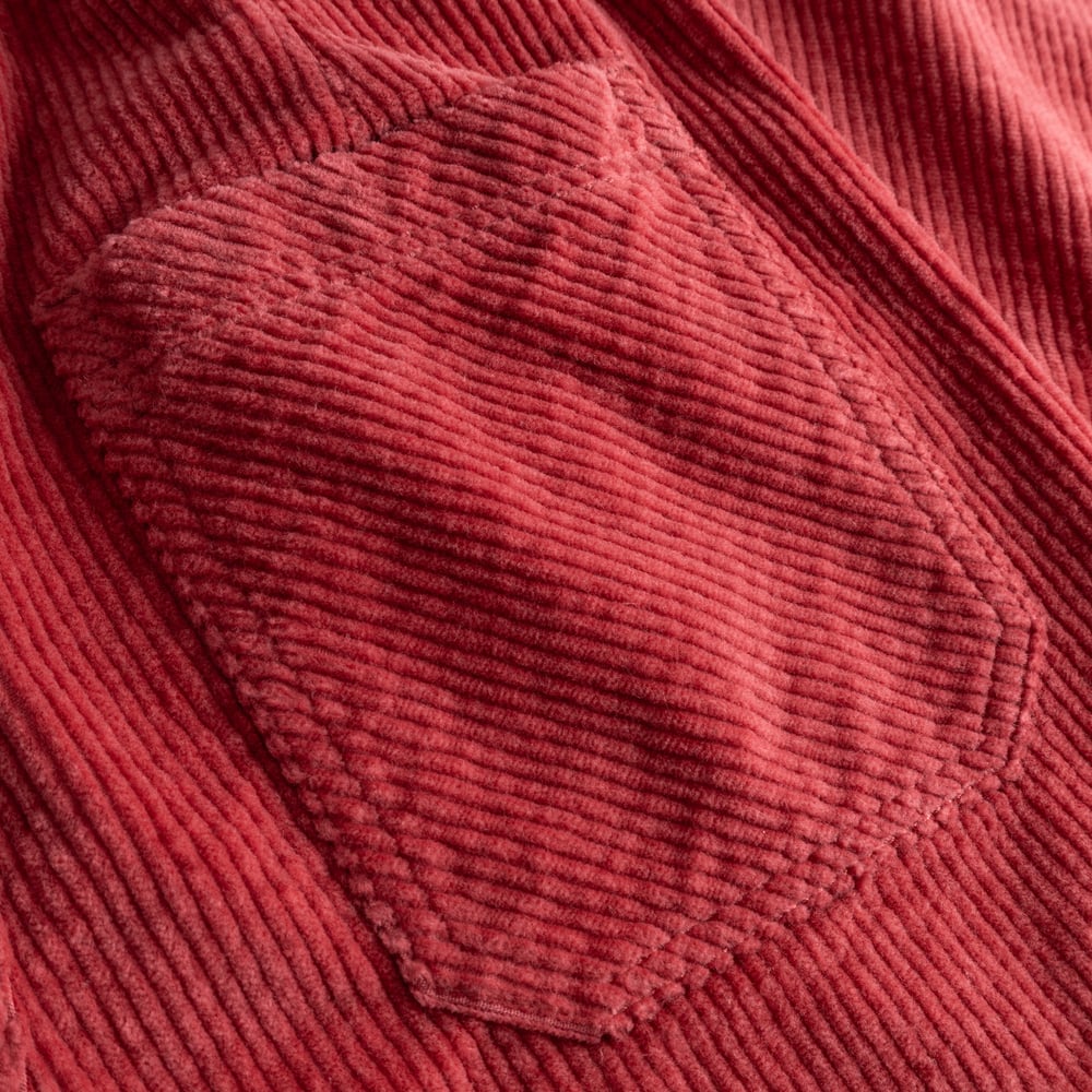Close-up detail of the soft corduroy fabric and back patch pocket on the Workwear Pants Vara in Holly Red.