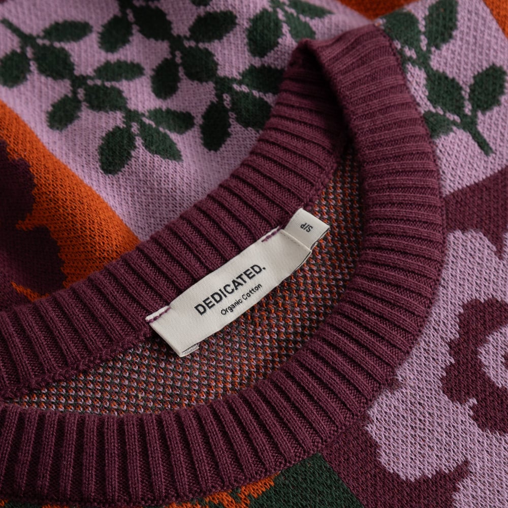 Close-up of the jacquard knit Sweater Arendal in Nature Check, showing the ribbed neckline and Dedicated label.