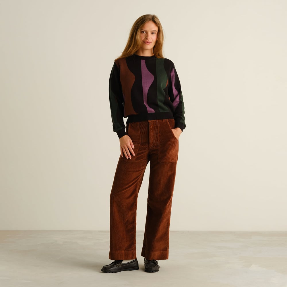 Model wears the Sweater Arendal Wavy Stripe Multi Color, styled with brown corduroy trousers and black loafers.