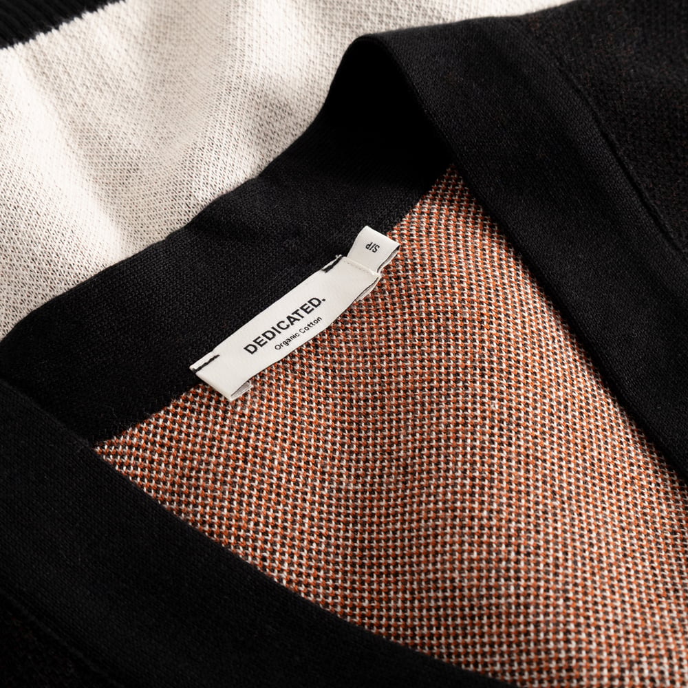 A close-up of the Cardigan Kanan Western's neckline, showcasing the fine knit texture and the Dedicated brand label.