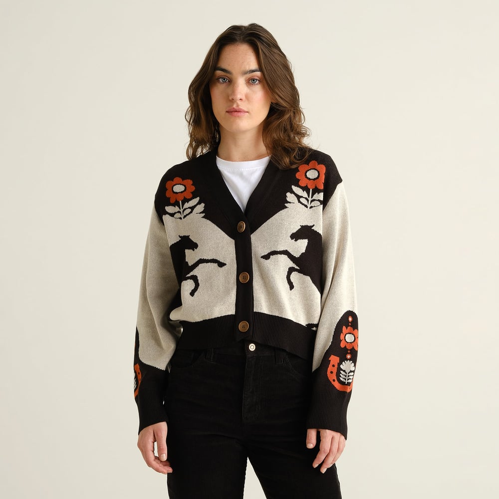 Model wears the Cardigan Kanan Western Multi Color, a knitted V-neck with a unique jacquard pattern of horses and flowers.