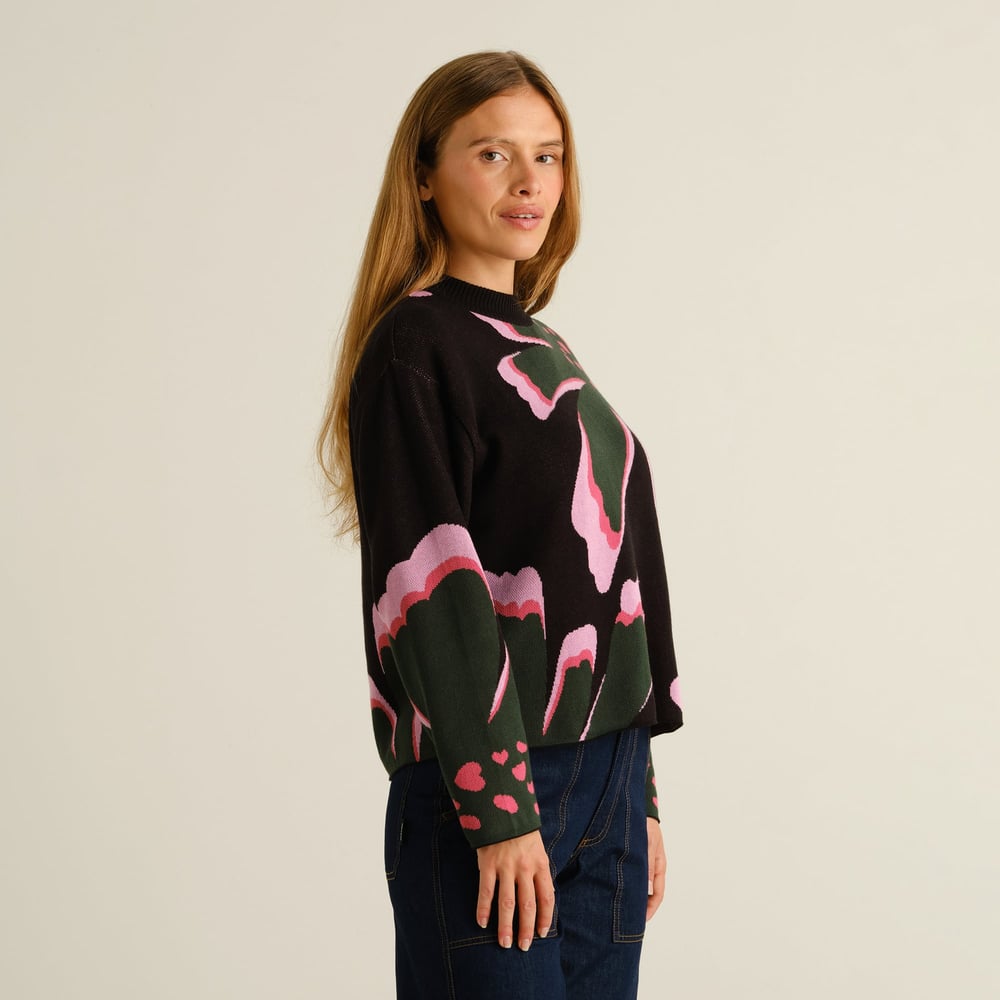 Close-up side view of a woman wearing the Dedicated Sweater Limhamn, featuring the colorful 'Big Bloom' floral pattern.