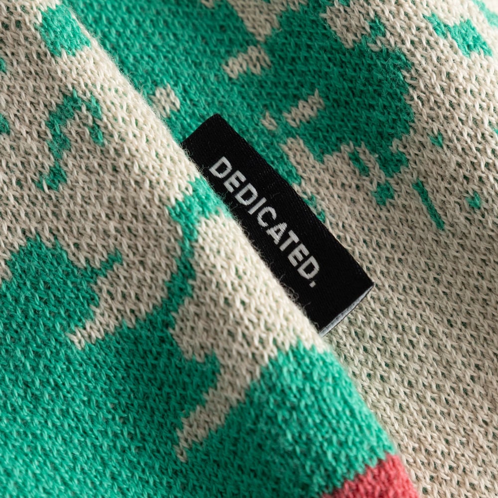 Detaljbild av det färgglada, jacquardstickade mönstret och Dedicated-etiketten på koftan Delsbo.