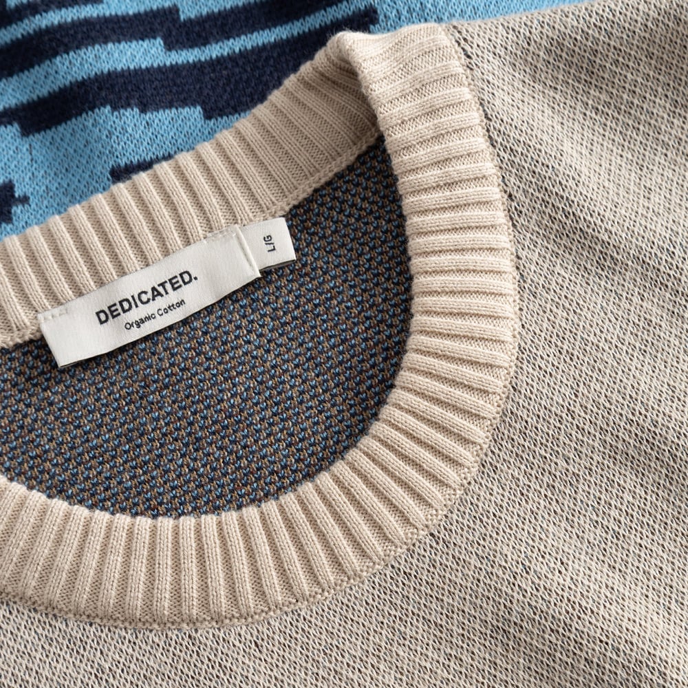 Detail shot of the Sweater Mora Man and Sea, showing the texture of the jacquard knit and the ribbed neckline with brand tag.