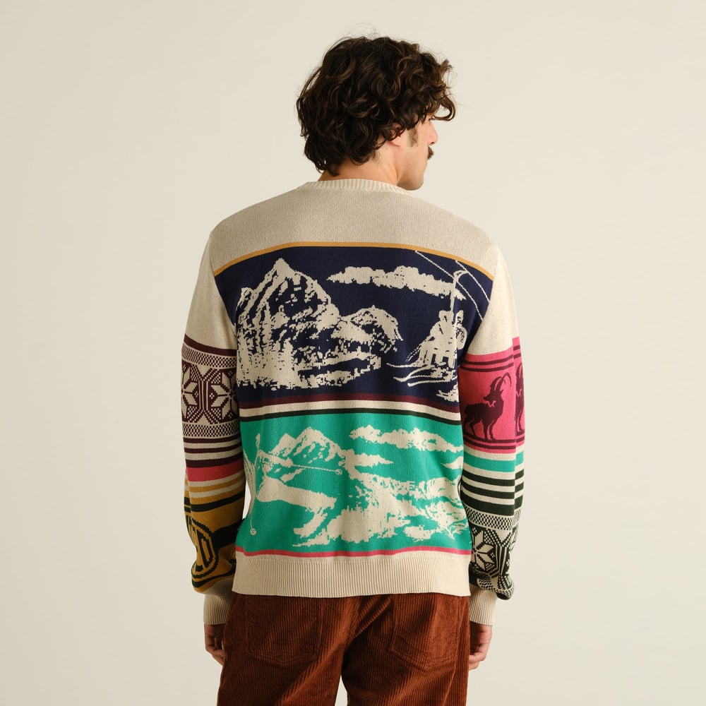 A model seen from behind wearing the Sweater Mora Retro Ski Blocks, showcasing its vibrant, multi-colored jacquard design.