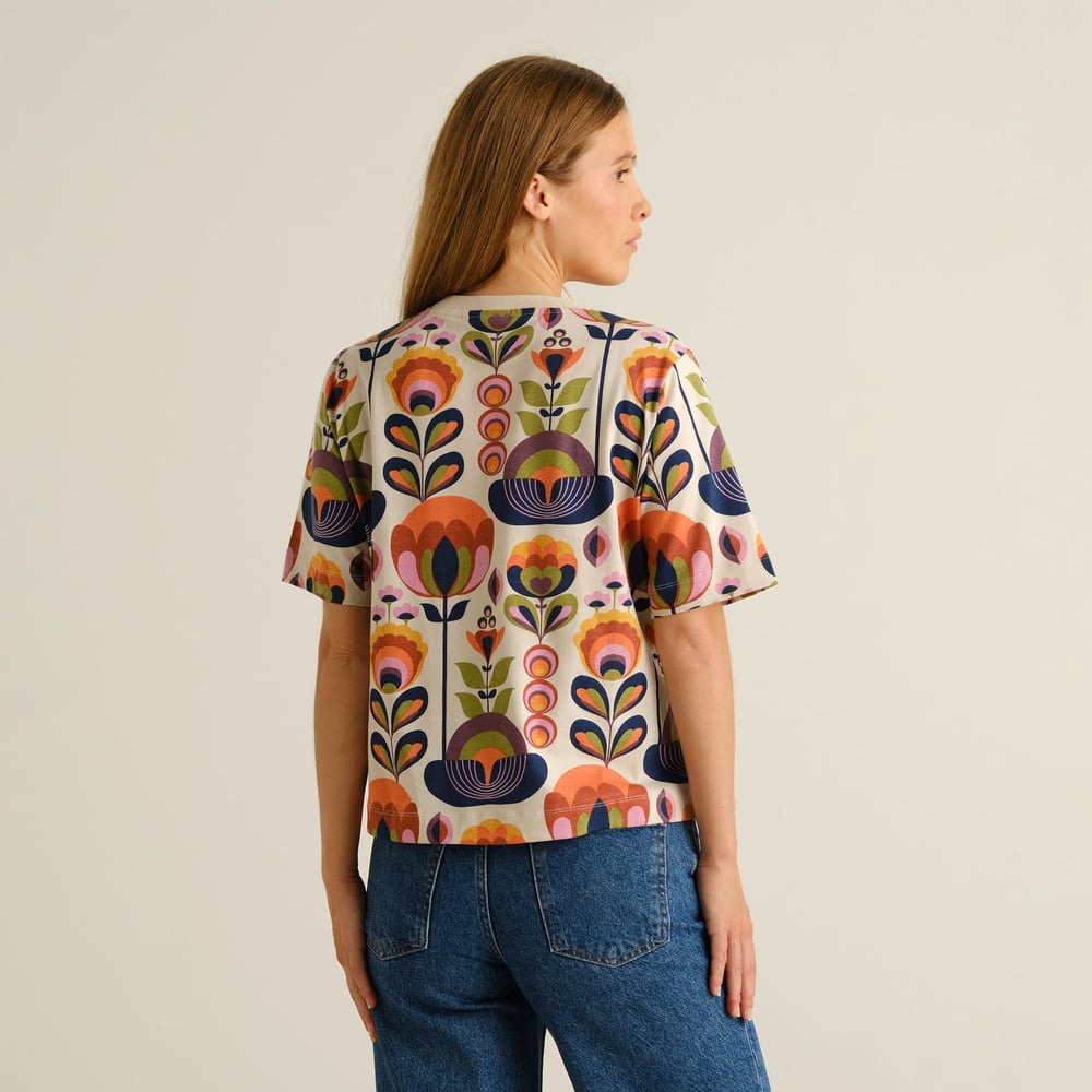 Model from the back wearing the Vadstena T-shirt in the colorful Autumn Harvest print with a pair of classic blue jeans.