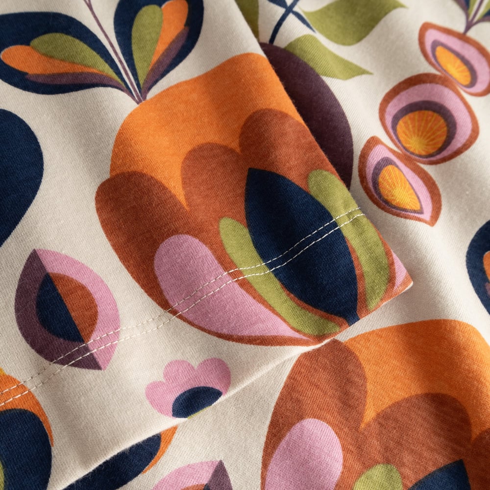 A detailed close-up of the T-shirt Vadstena, highlighting the colorful retro-style Autumn Harvest print on the sleeve.