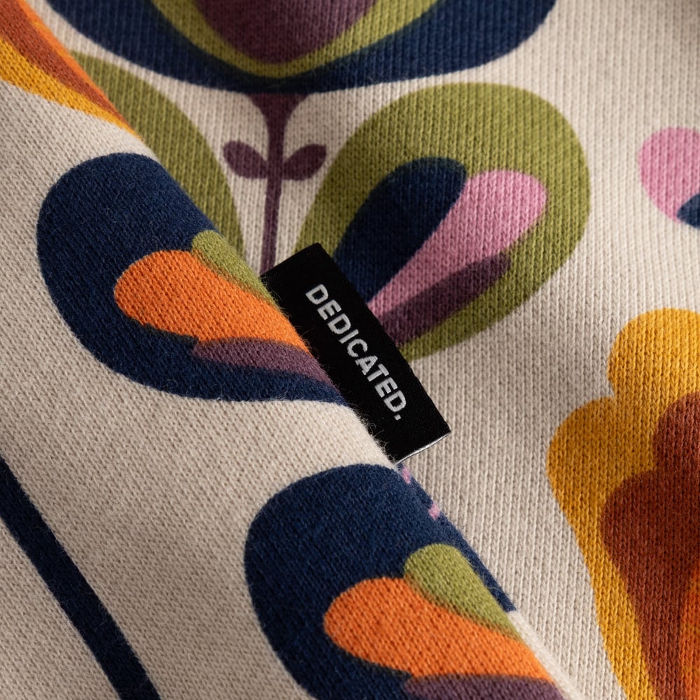 A close-up of the Ystad Sweatshirt in Autumn Harvest print, showing stylized flowers and the black Dedicated brand tab.