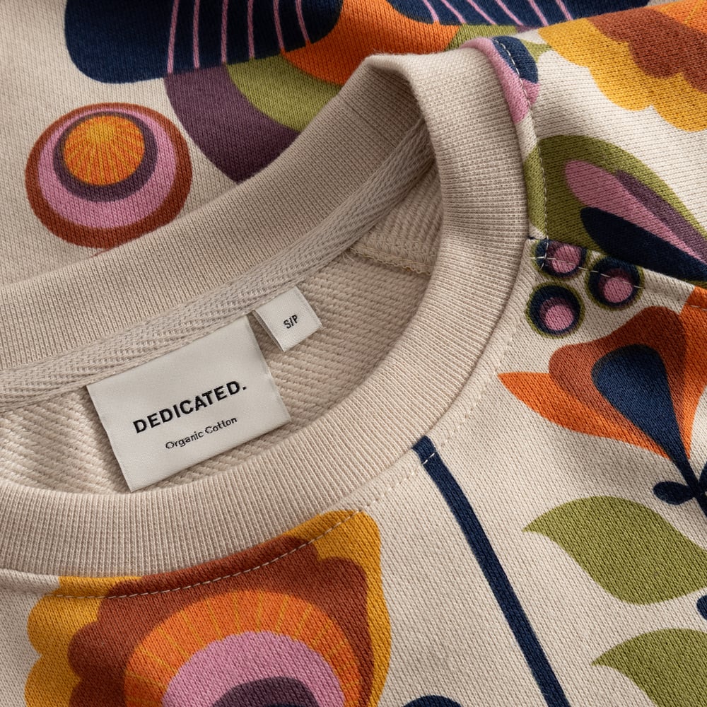 Close-up of the Ystad sweatshirt's ribbed neckline, showing the fun, retro Autumn Harvest print and brand label.