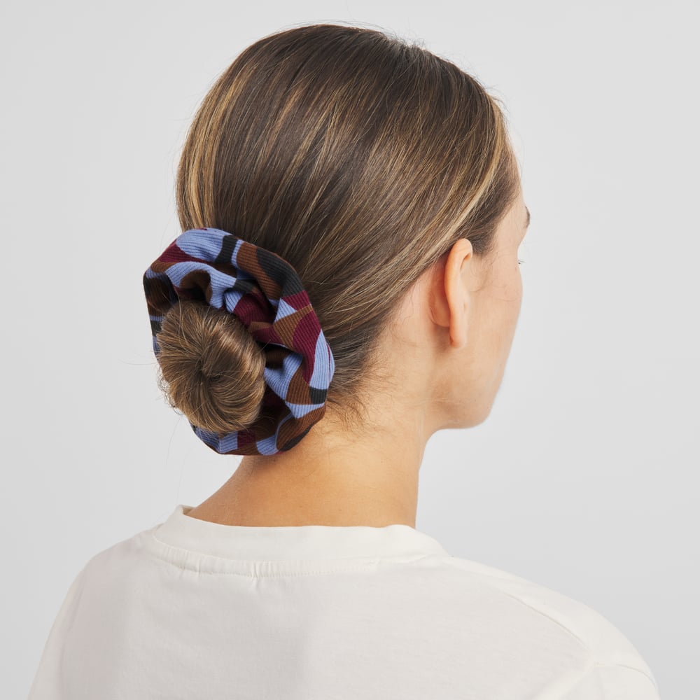 Rückansicht eines Models mit einem Dutt, der mit dem bunten Retro-Geo-Scrunchie gestylt ist.