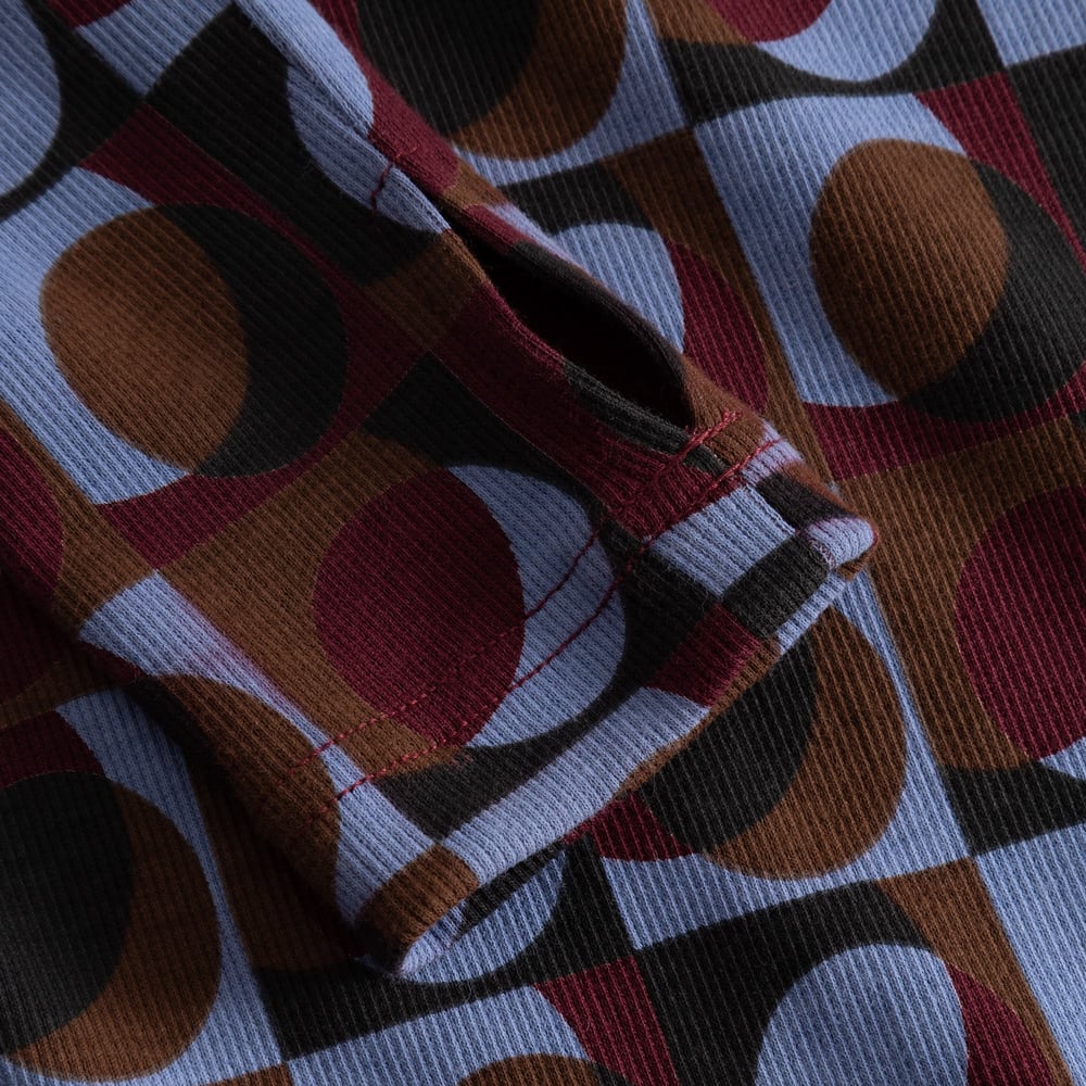 Close-up on the sleeve of the Rib Top Malma, showing the thumbhole detail and the colorful Retro Geo print on ribbed fabric.