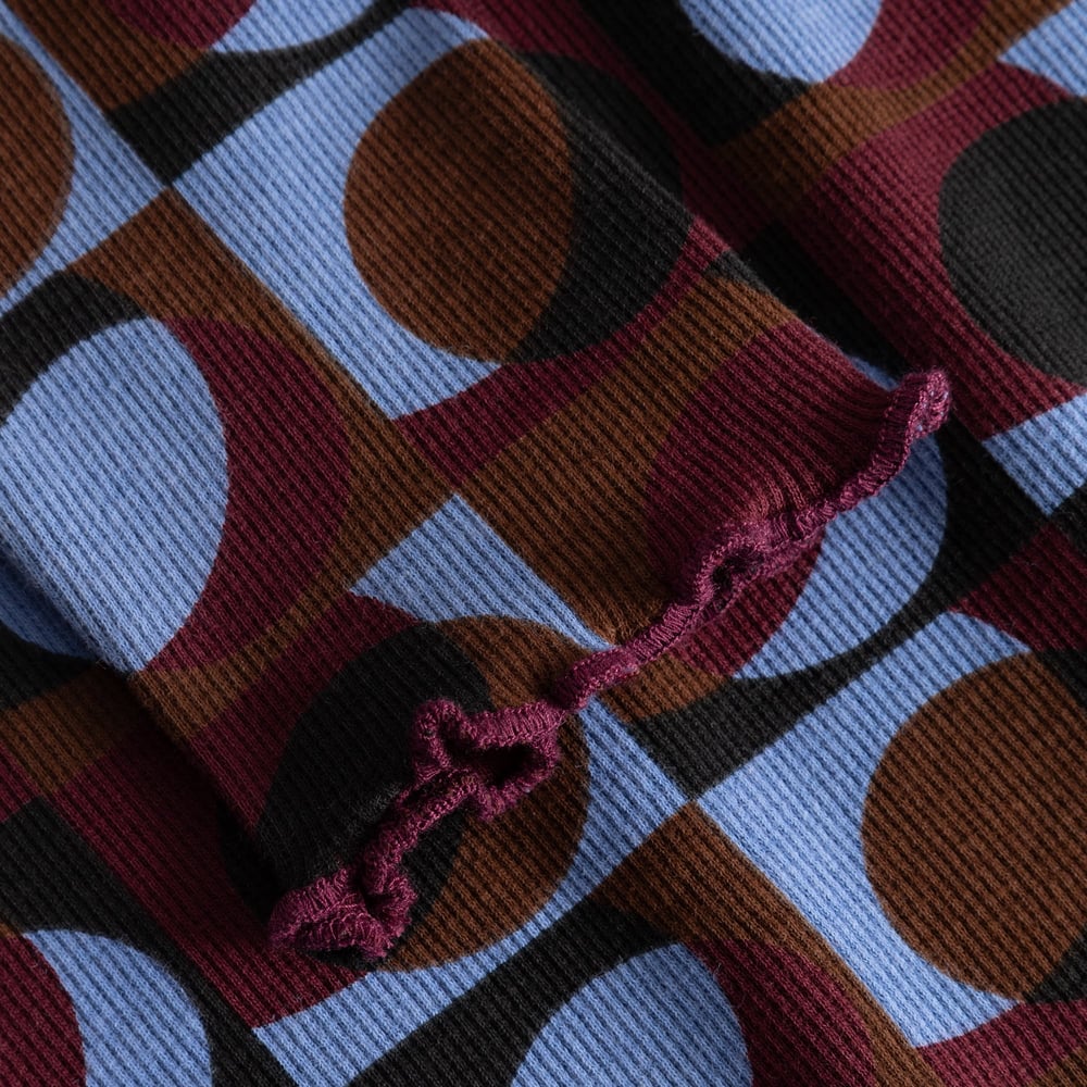 A close-up view of the Rib Dress Lofta, highlighting the retro geo pattern and lettuce hem detail on the ribbed fabric.