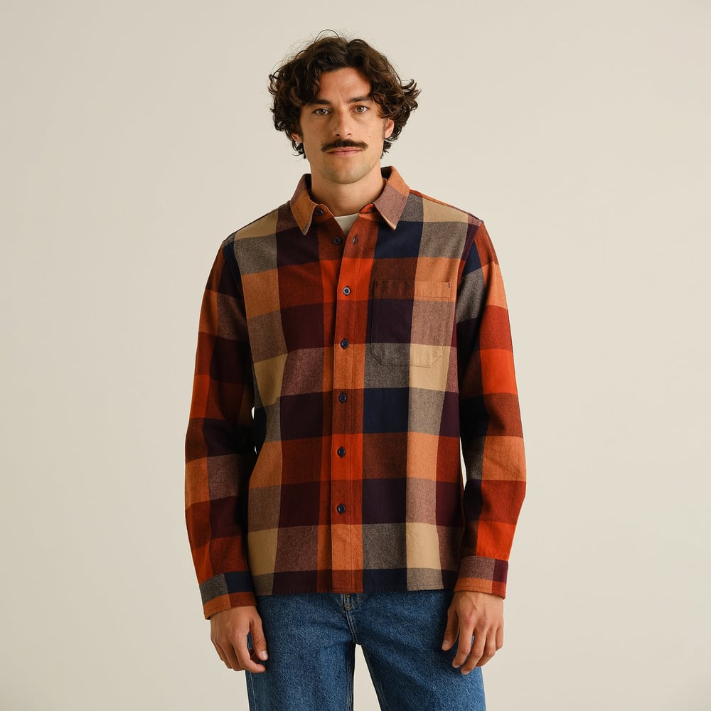 Front view of a model wearing the relaxed-fit Rute Flannel Check Shirt in a muted multi-color plaid.