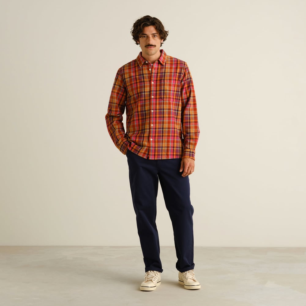A model wears the colorful Rute Flannel Madras Check Shirt, styled with classic navy trousers and white sneakers.