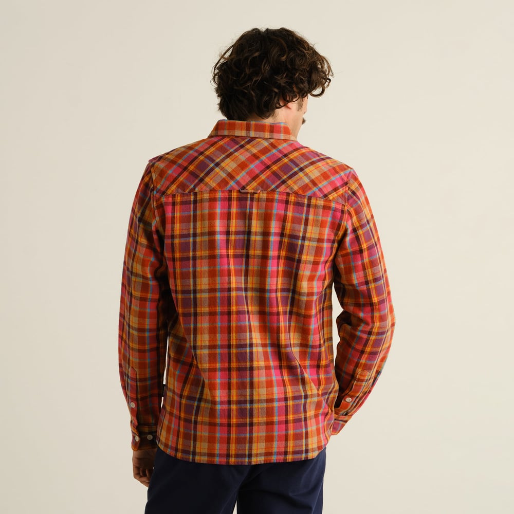 A man seen from behind wearing the relaxed-fit Rute Flannel Shirt in a vibrant multi-colored Madras check pattern.