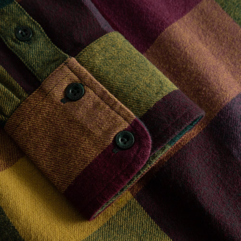 A close-up of the buttoned cuff on the Arboga Flannel Shirt, showcasing the soft, brushed fabric in a bold multi-color plaid.