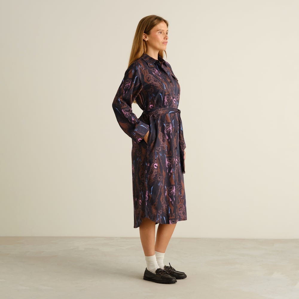 A model wears the Kvilla Shirt Dress in the Owls Multi Color print, seen from the side with her hands in the pockets.