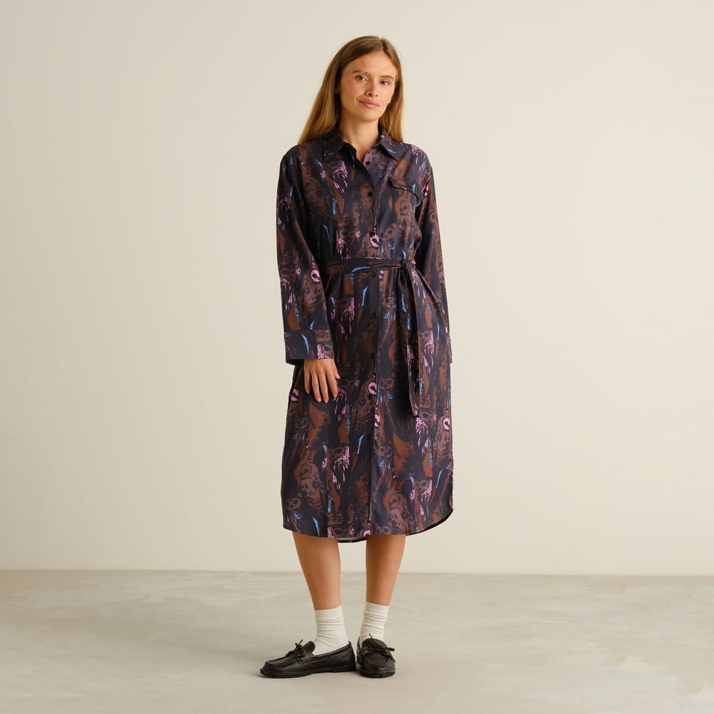 Woman wearing the Kvilla Shirt Dress in a playful multi-colored owl print, styled with socks and loafers in a studio.