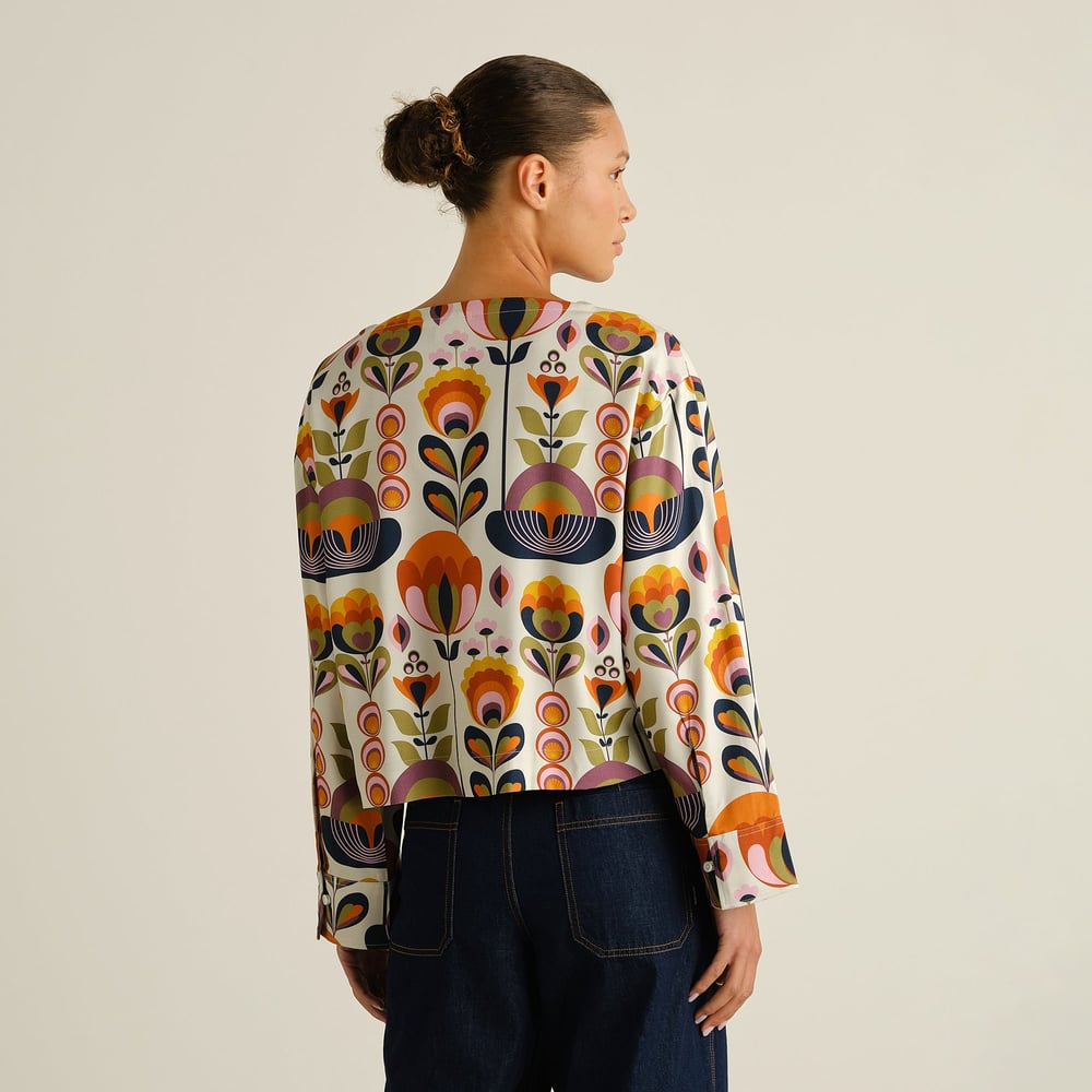 Model from the back wears the boxy Top Udda in the vibrant Autumn Harvest print, styled with dark blue jeans.