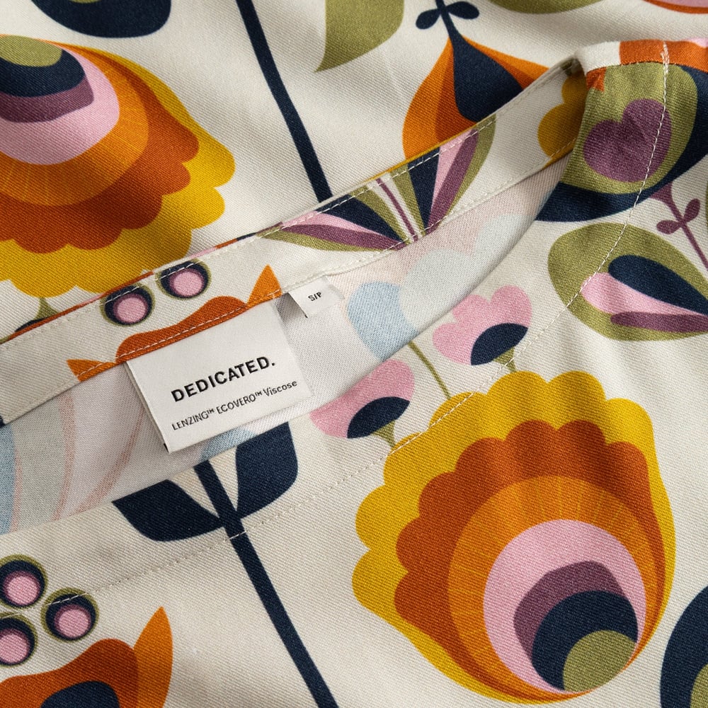 Detail shot of the Top Udda's neckline, showcasing the colorful Autumn Harvest print and the Dedicated label.