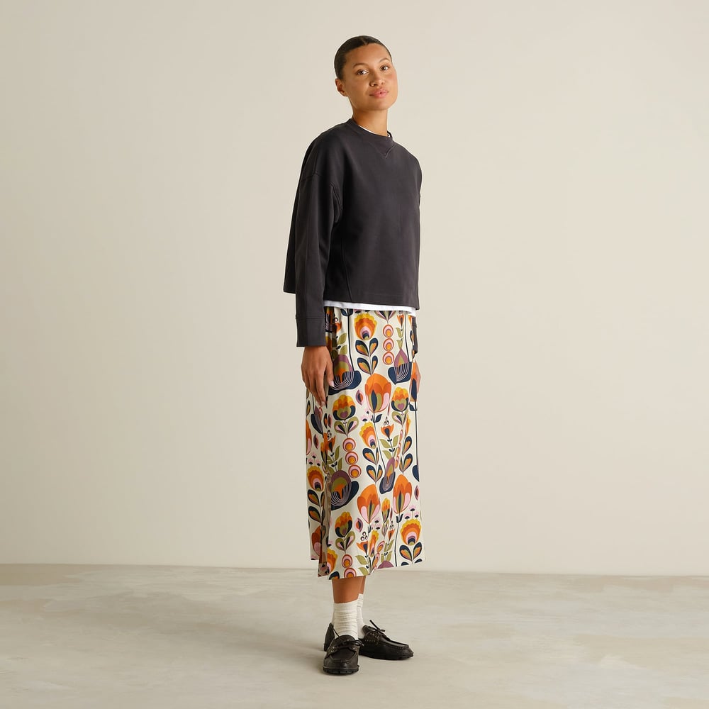 Side view of a model wearing the Skirt Viken Autumn Harvest, styled with a dark sweatshirt, white socks and black loafers.