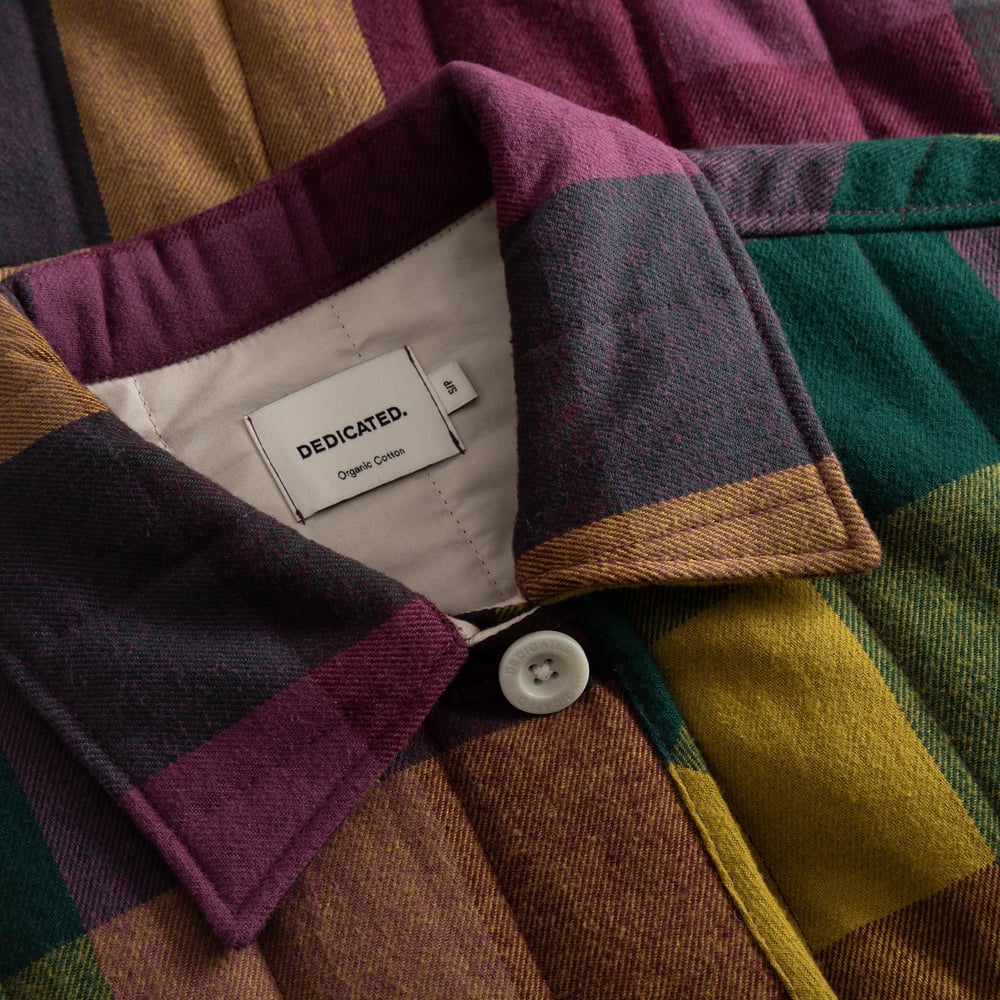 Närbild på den quiltade kragen och Dedicated-etiketten på den flerfärgade flanelljackan Voxtorp.