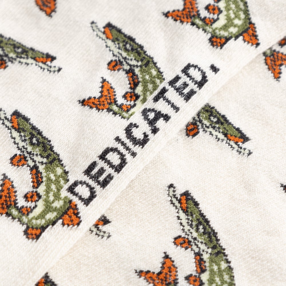 A detailed shot of the off-white Sigtuna Pikes socks, showcasing the intricate fish pattern and the classic Dedicated logo.