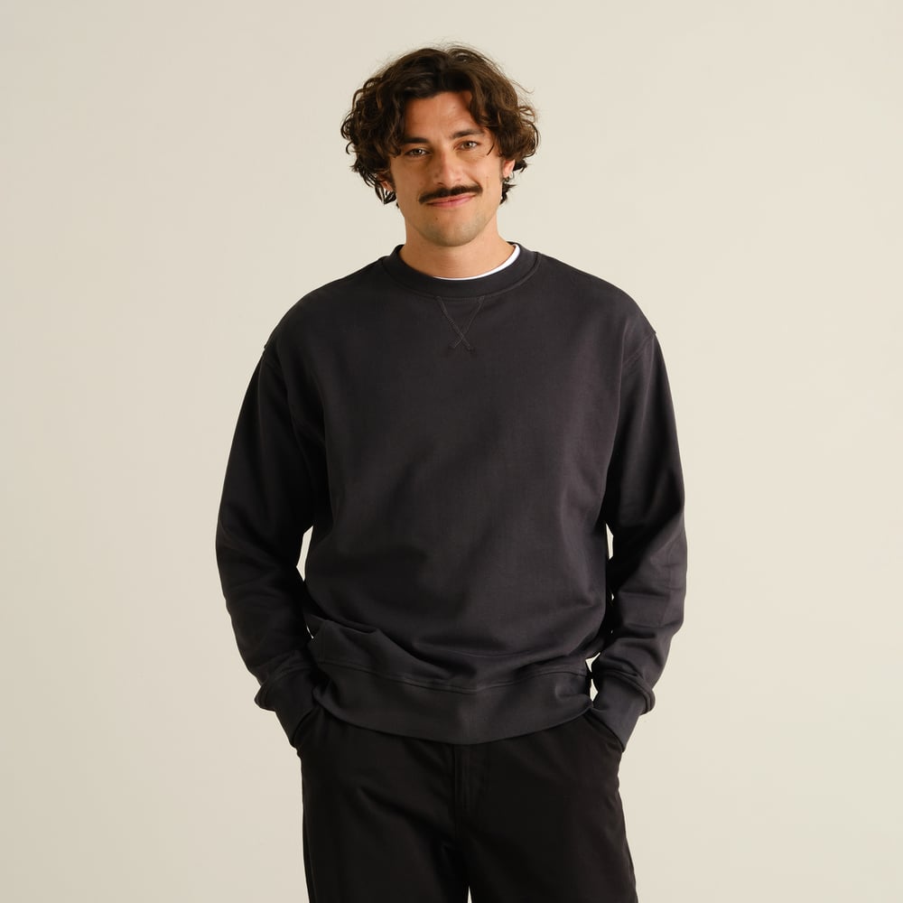 A model with curly hair and a mustache wears the relaxed-fit Sweatshirt Bettna in Phantom Black.