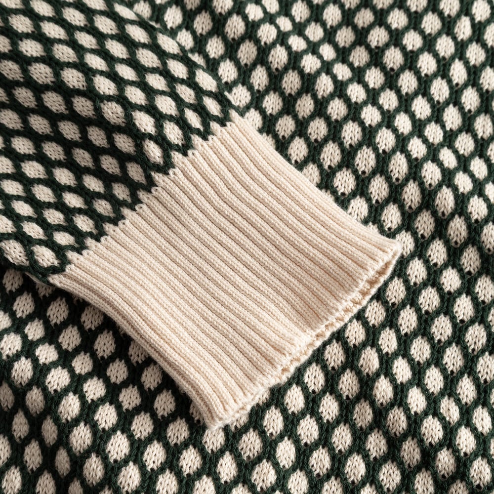 Närbild på ärmen på Kanan Cardigan, som visar den texturerade bubbelstickningen i mörkgrönt och vaniljvitt.