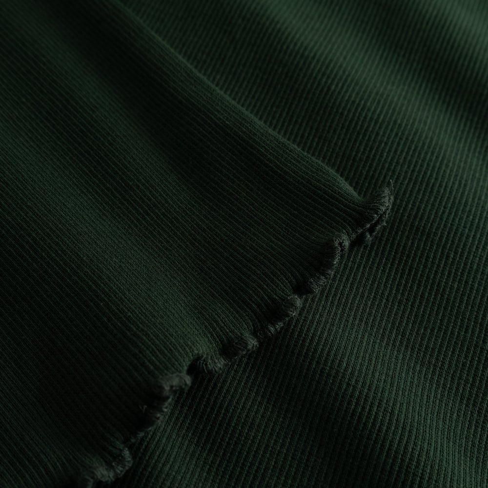 Close-up of the Rib Dress Lofta in Dark Green, highlighting the soft ribbed fabric and the delicate lettuce edge detail.