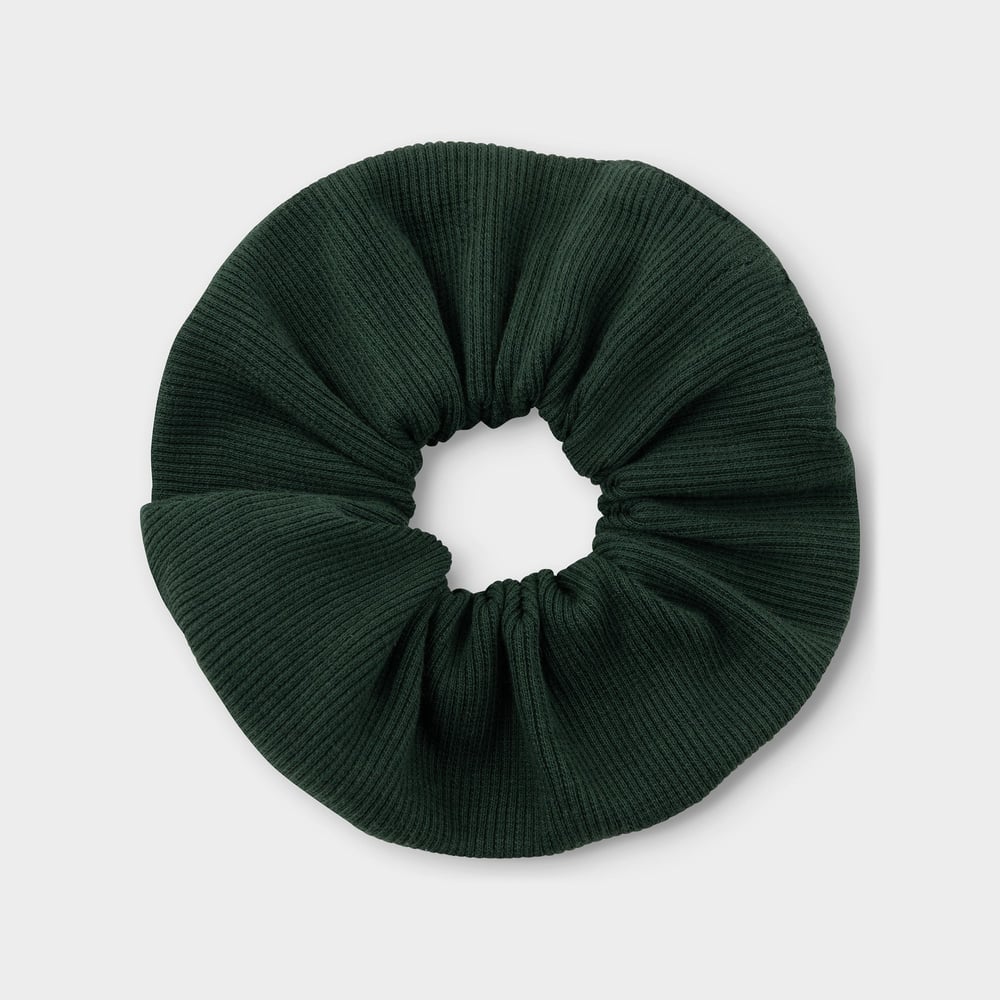 A dark green scrunchie with a ribbed texture, seen from above on a light background.