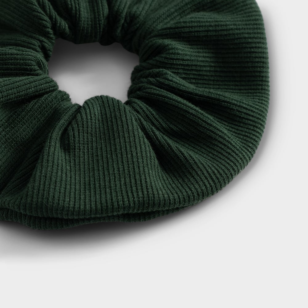 Close-up of the dark green ribbed scrunchie, highlighting the soft texture of the fabric.