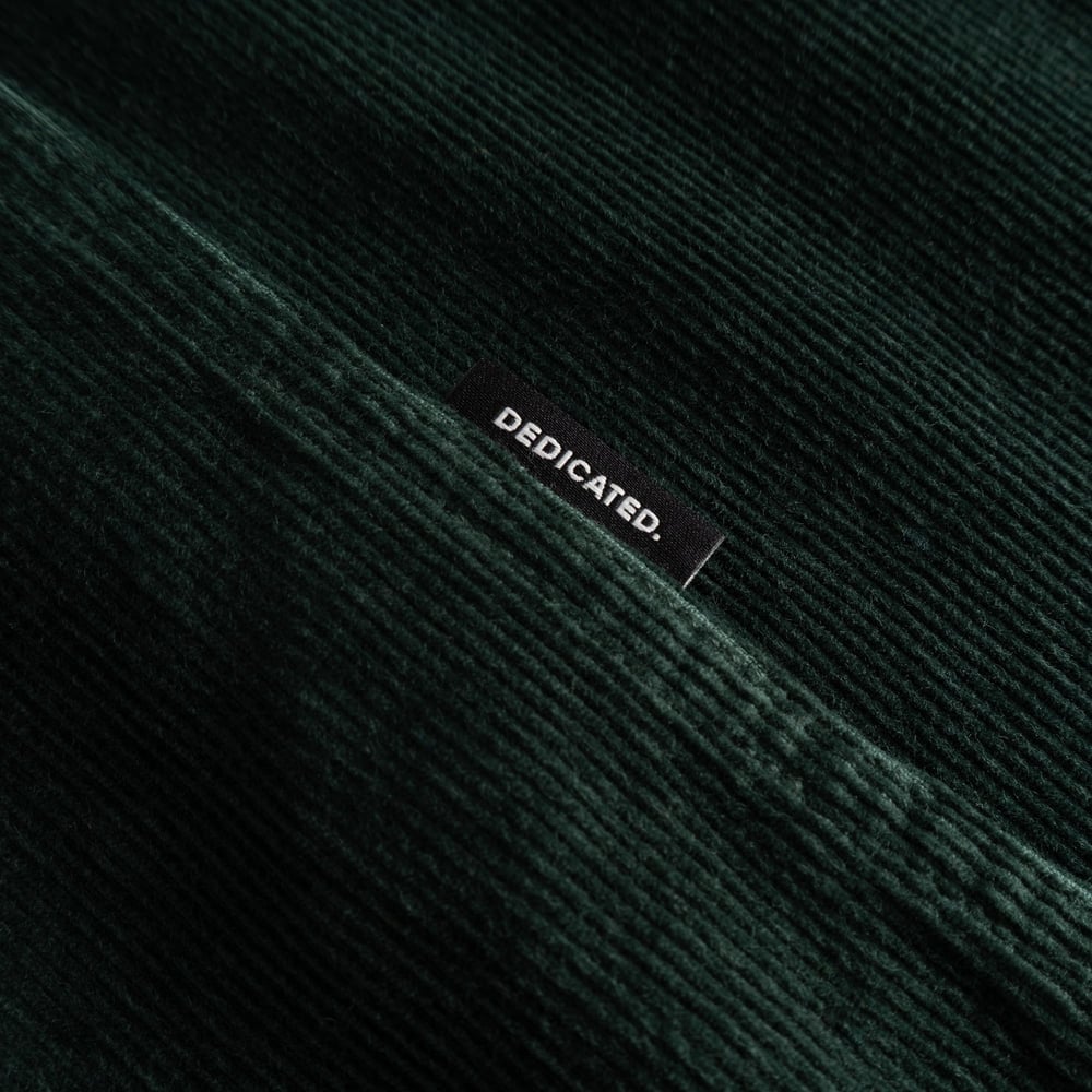 Close-up of the Shirt Varberg Corduroy in dark green, showing the fine texture and the small Dedicated brand label.