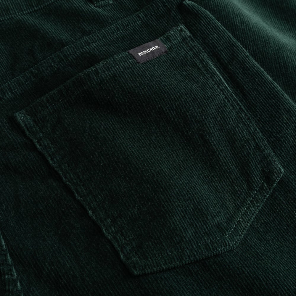 A close-up of the back pocket on the Pants Ryda in Dark Green, showcasing the rich corduroy texture and the Dedicated label.