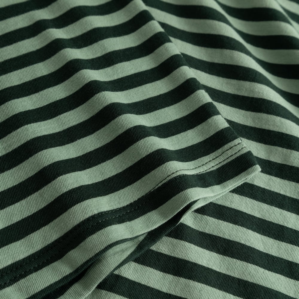 Close-up of the Top Humledal's soft jersey fabric, featuring dark green and granite green stripes and sleeve hem detail.