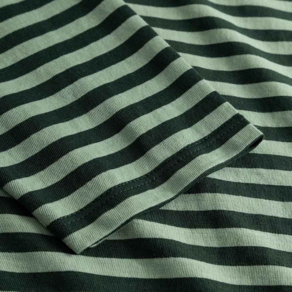 A detailed close-up of the sleeve on the Top Humledal, showing the dark green and granite green striped organic cotton.